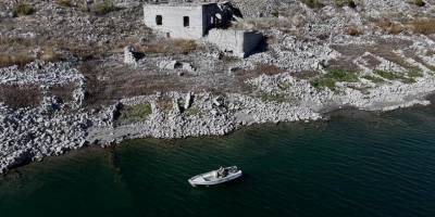 Su altında kalan mahallesinin üzerinde balık avlıyor